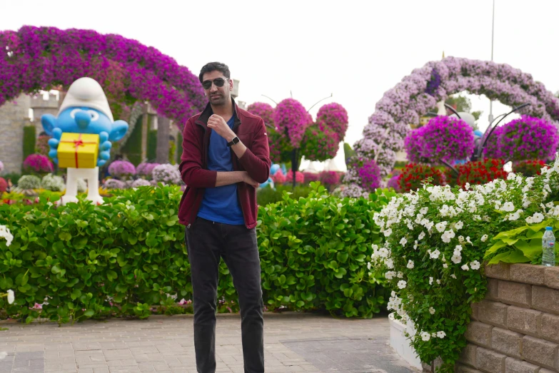 a man stands near several flowers, taking a picture