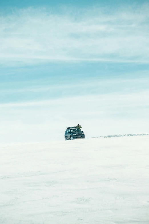two vehicles driving through an open field with no snow