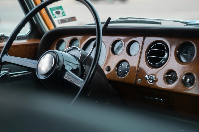 the dashboard of a car with brown leather and a wood steering wheel