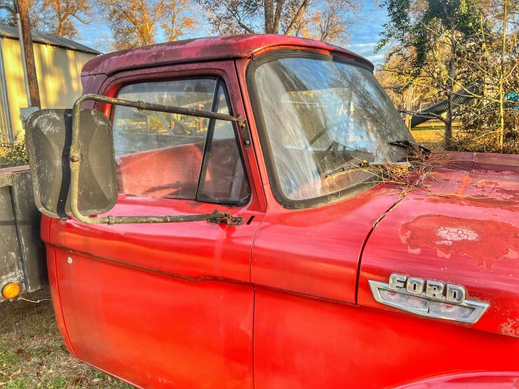 an old red truck parked in the grass