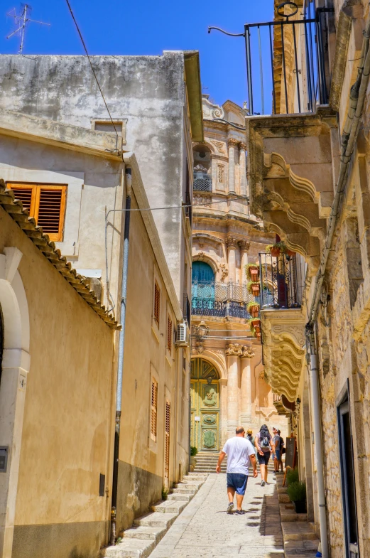 people walking down an alley lined with old buildings