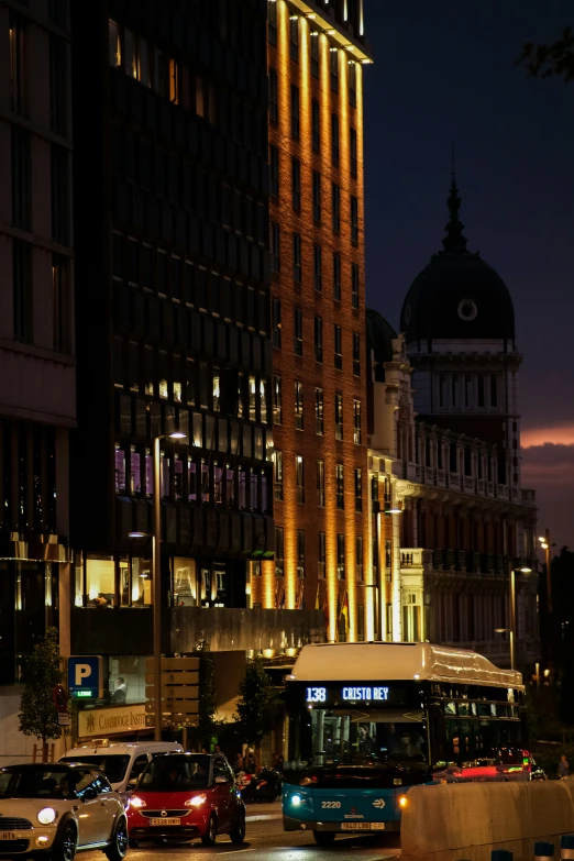 cars wait on a busy street with large buildings in the background