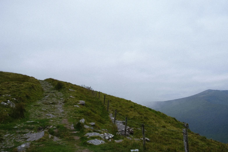 three people standing on a hill with a few fences in the grass