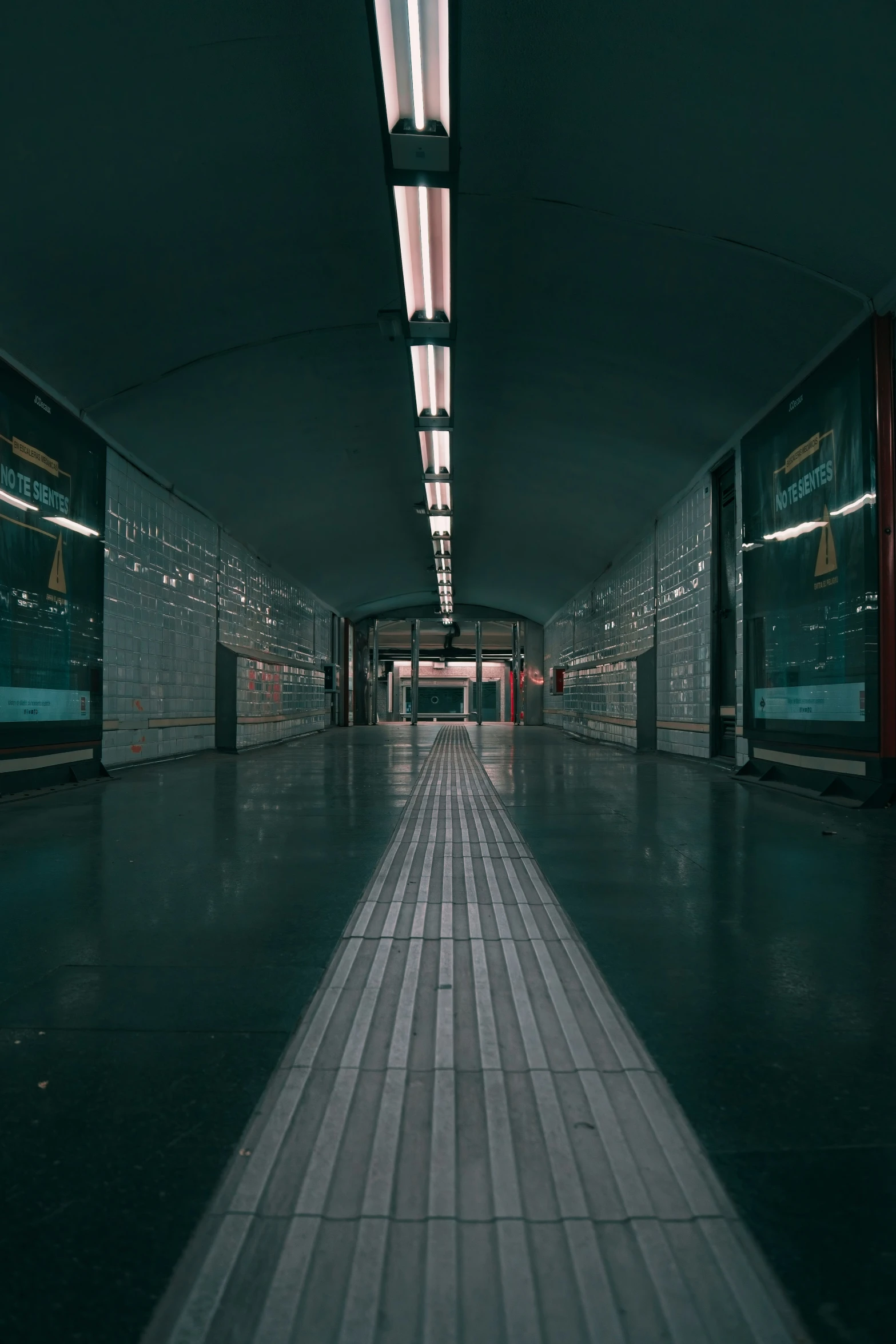 long walkway lined with metal posts in a dark room