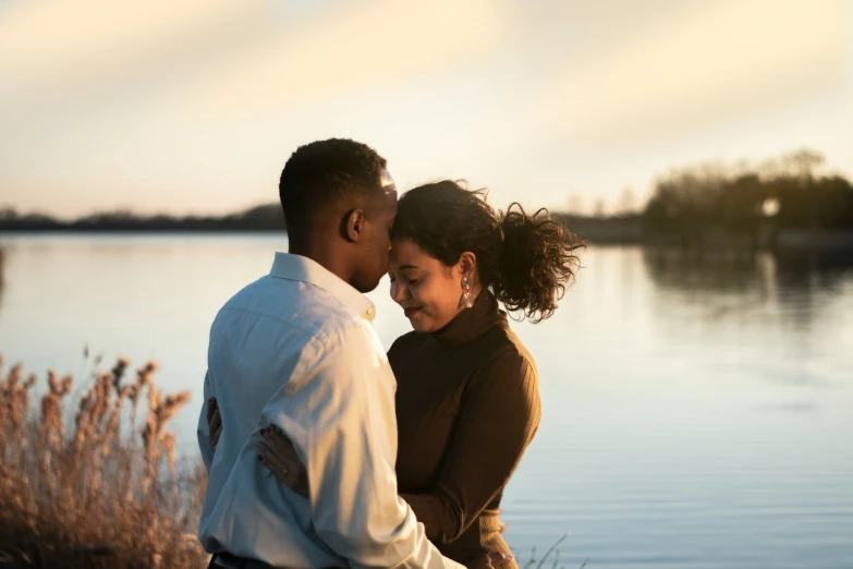 a man and woman holding each other by the water