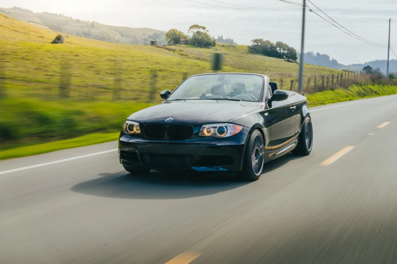 a black bmw convertible is driving down the road