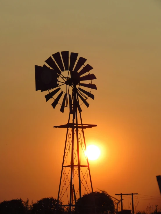 the sun rising over an old windmill in the sky