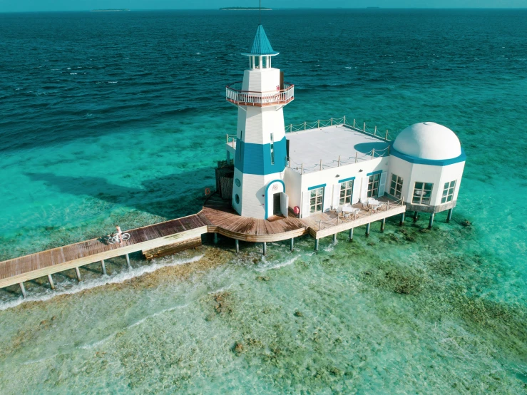 a lighthouse at the end of a pier in clear blue water