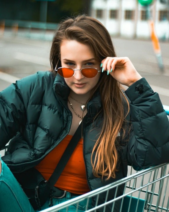 a young lady holding her sunglasses while sitting in a shopping cart