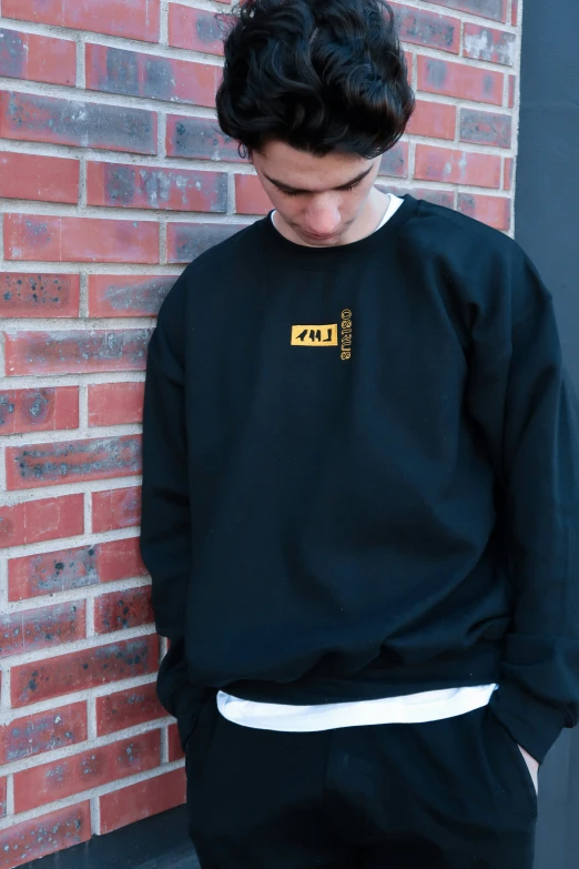 a young man standing next to a brick building