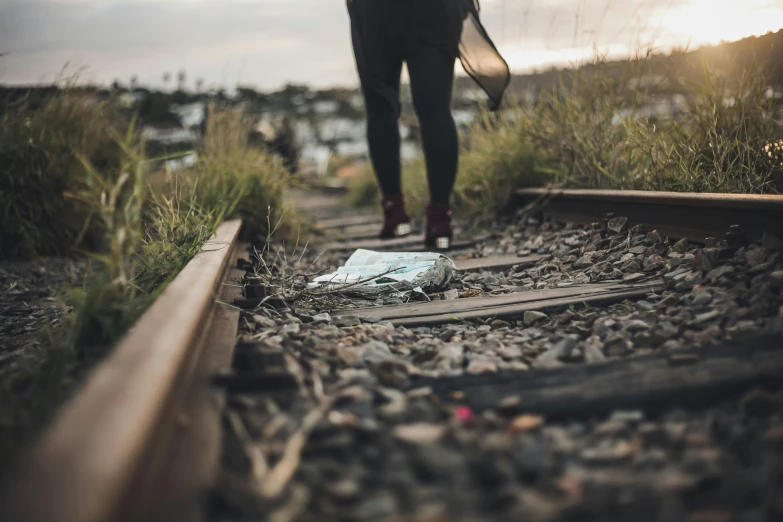 person walking down the railway line with a book