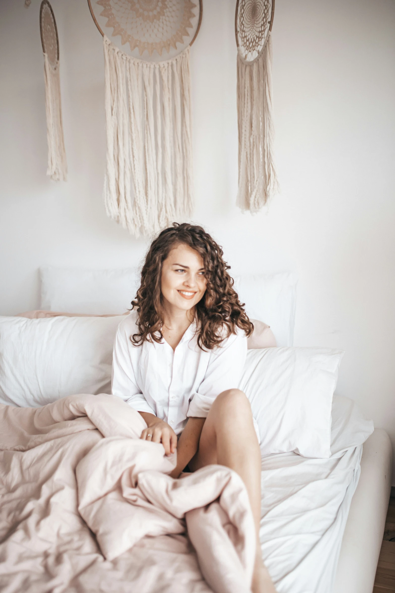 a woman in white laying on bed with a pink blanket