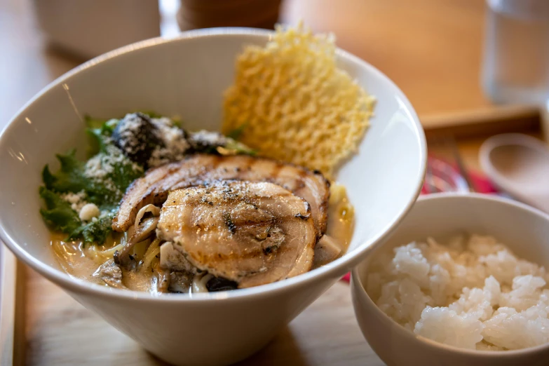 a bowl with chicken, rice and other foods on a table