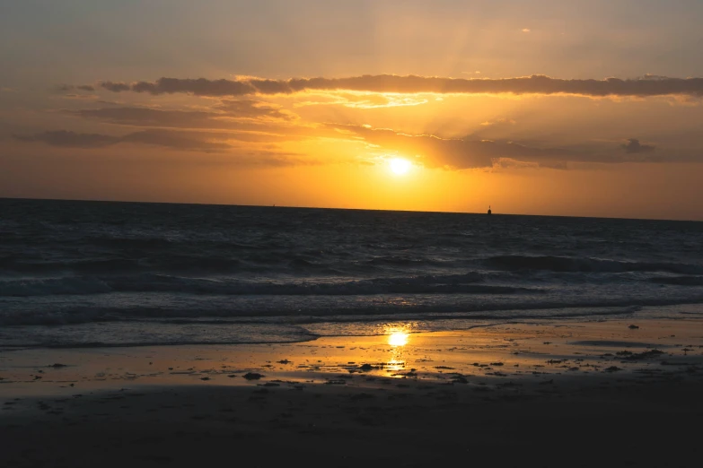 the sun is setting over the water at the beach