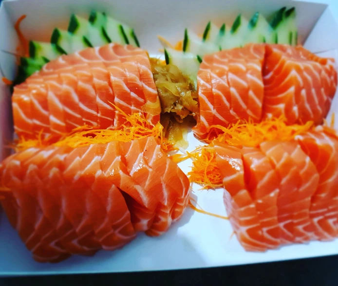 several sushi pieces of salmon sitting in a square white box