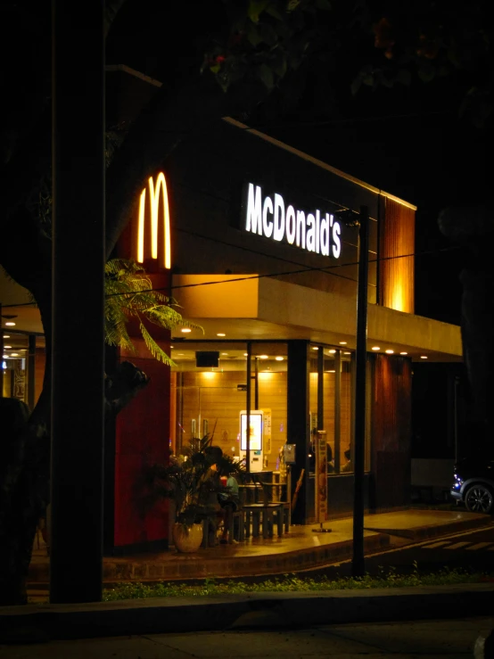 a mcdonald's is lit up at night in a darkened street