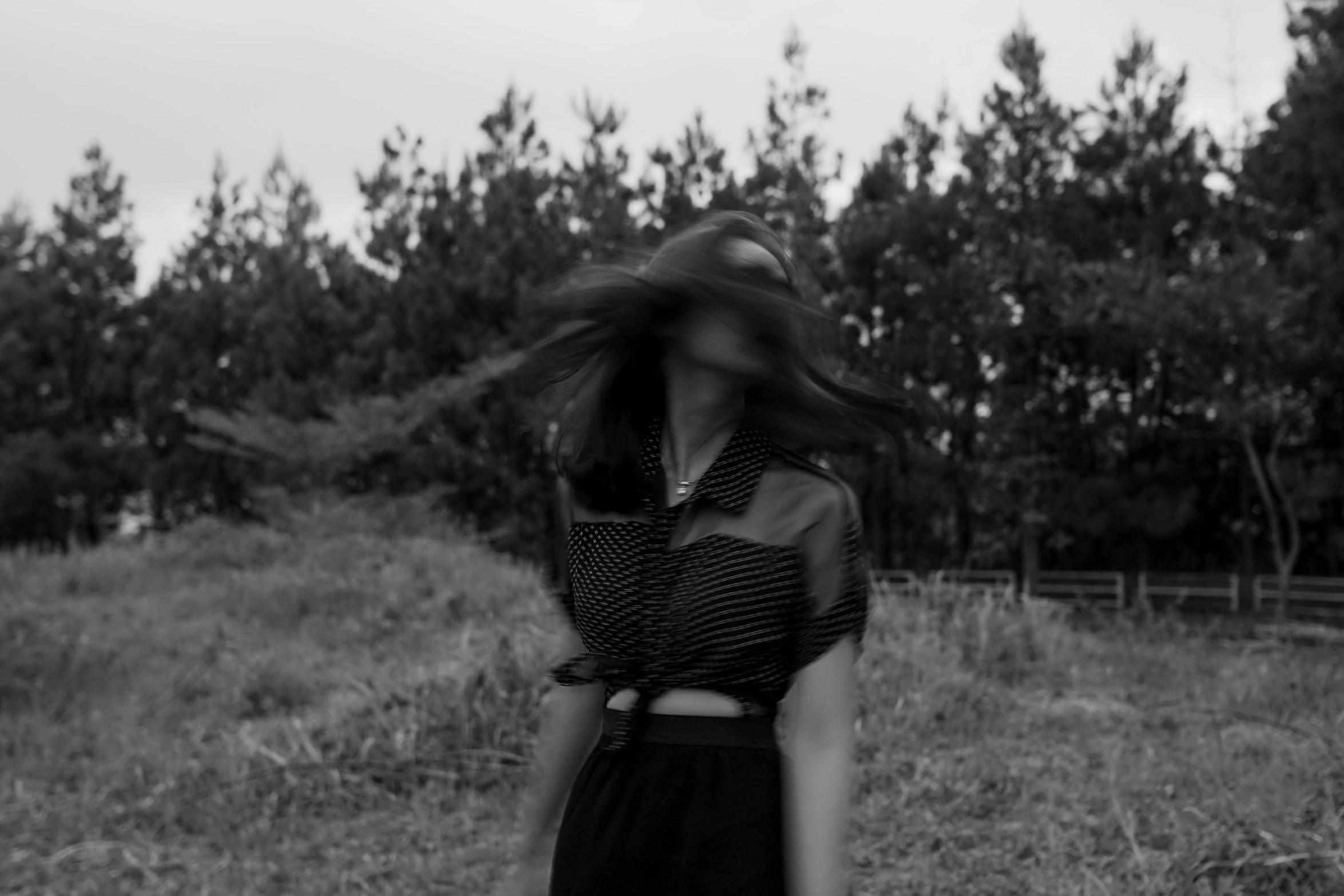 a woman holding her hair in front of trees