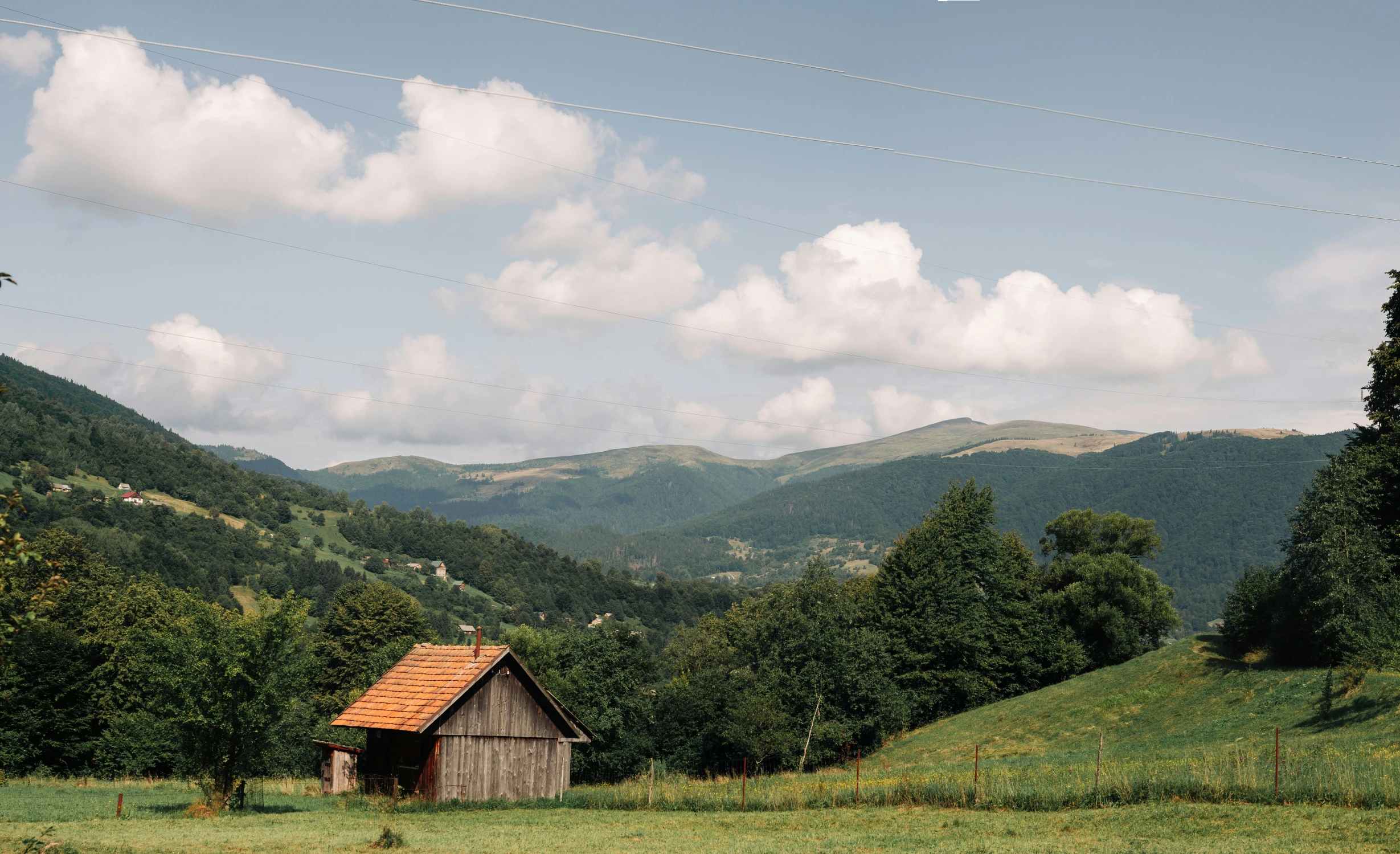 a rustic cabin nestled in the hills with trees and mountains