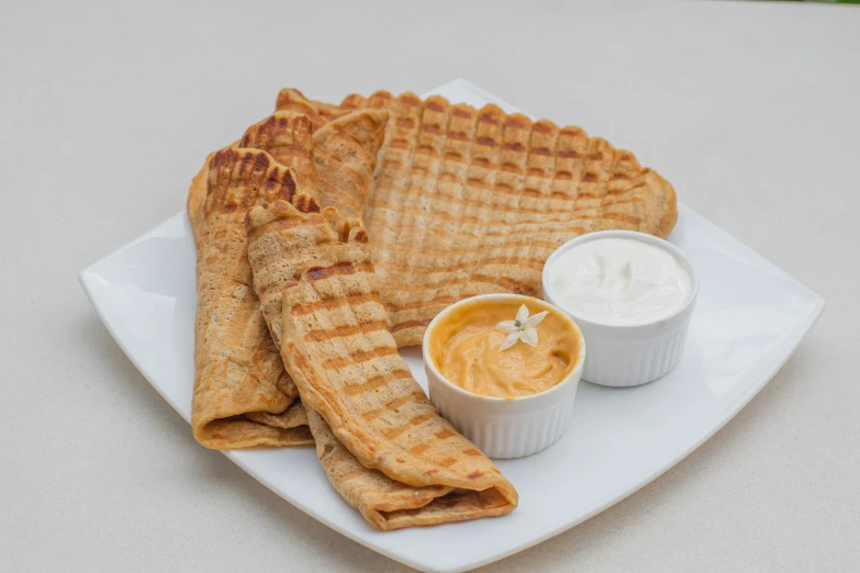 plate of waffles and dips with container of cheese dip