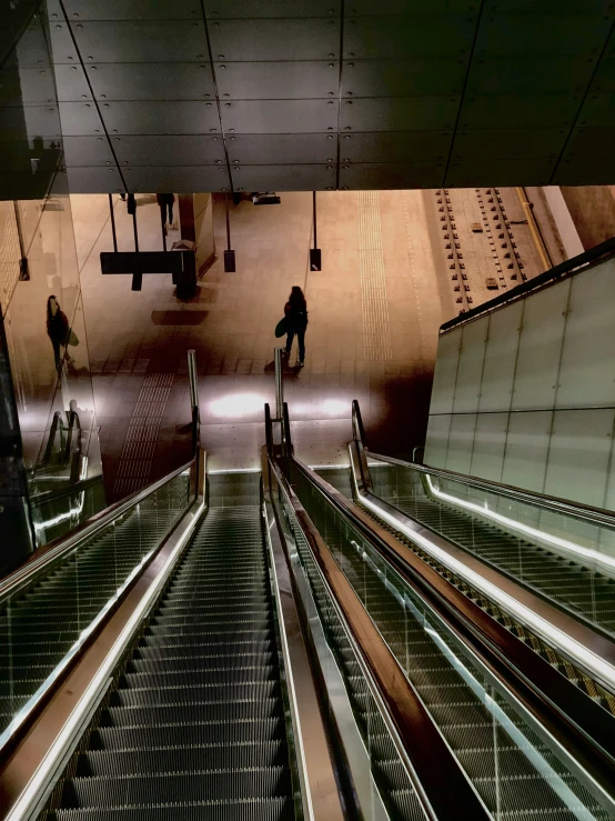 escalators in a station with some people on the other side