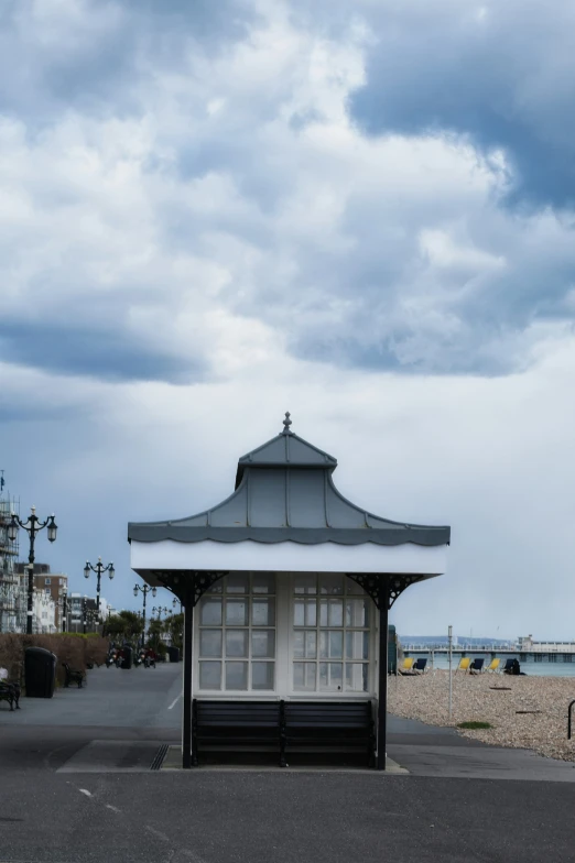 a small white building by the sea under a cloudy sky