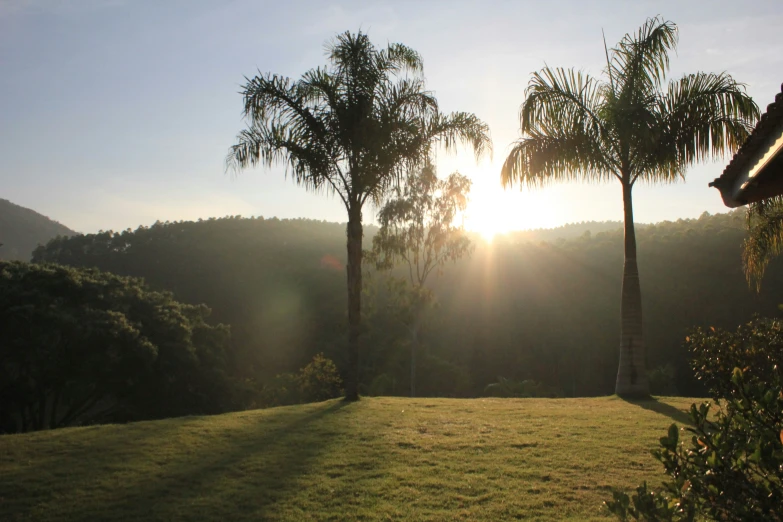 the sun is rising behind the mountains with palm trees