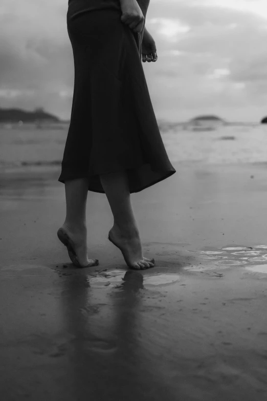 black and white image of a woman standing on beach