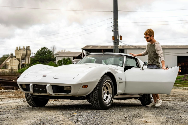 a girl standing next to a white vintage sports car