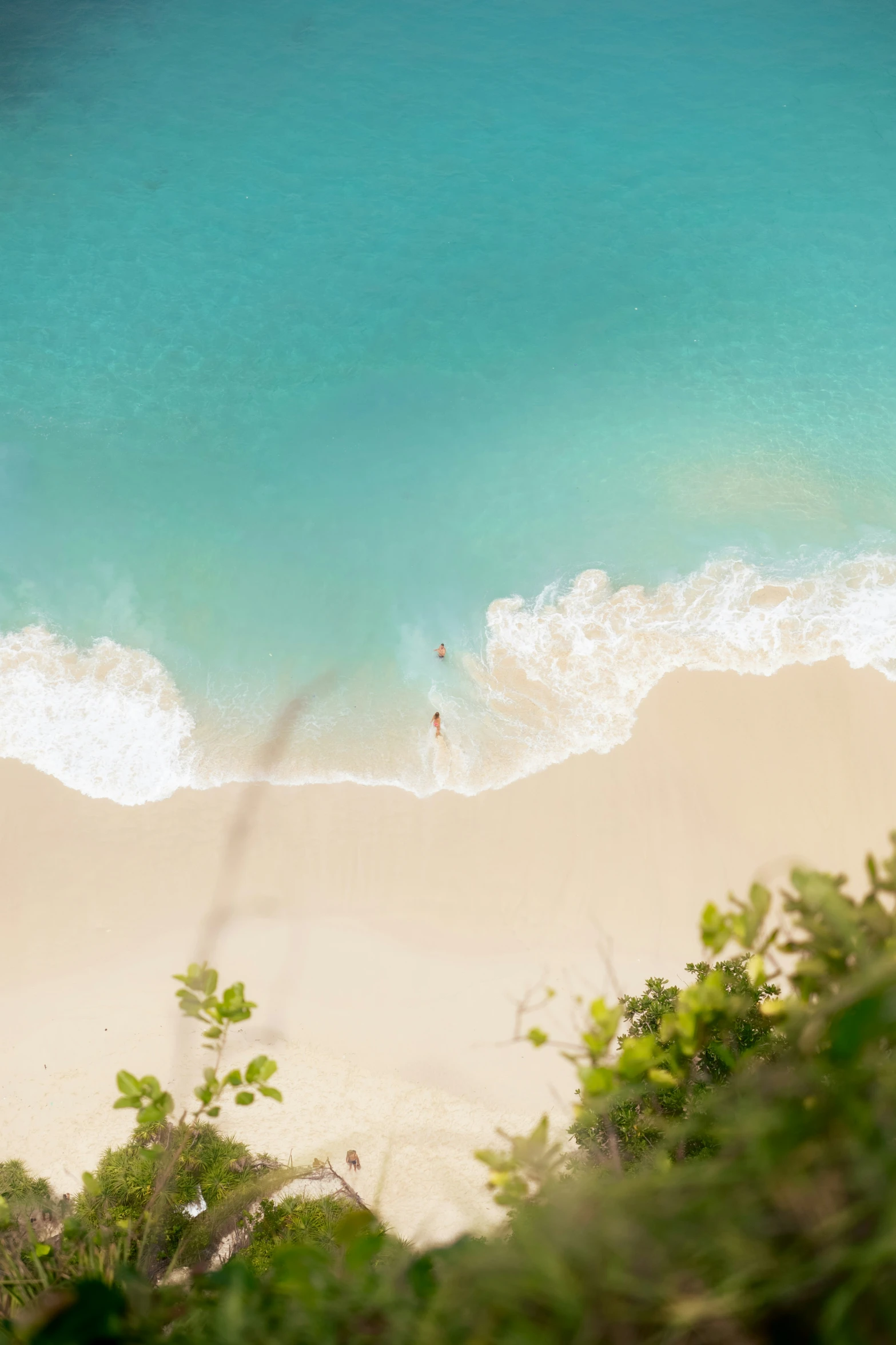 an aerial s of a sandy beach with two swimmers