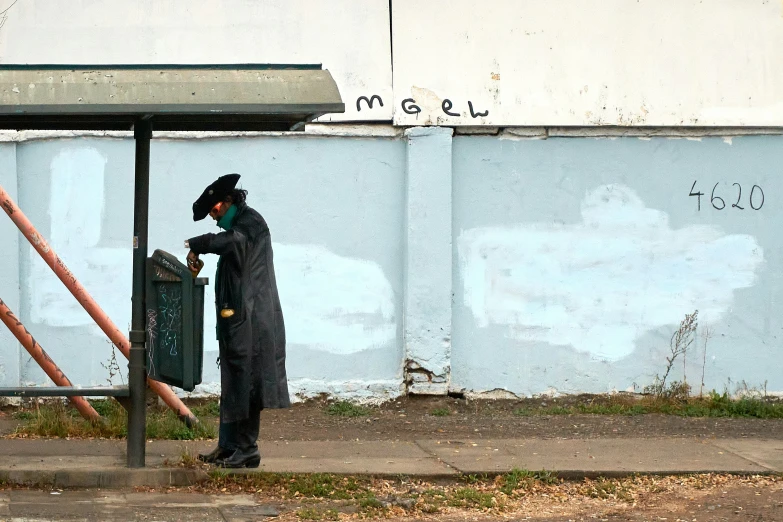 a man dressed in black stands next to a street sign