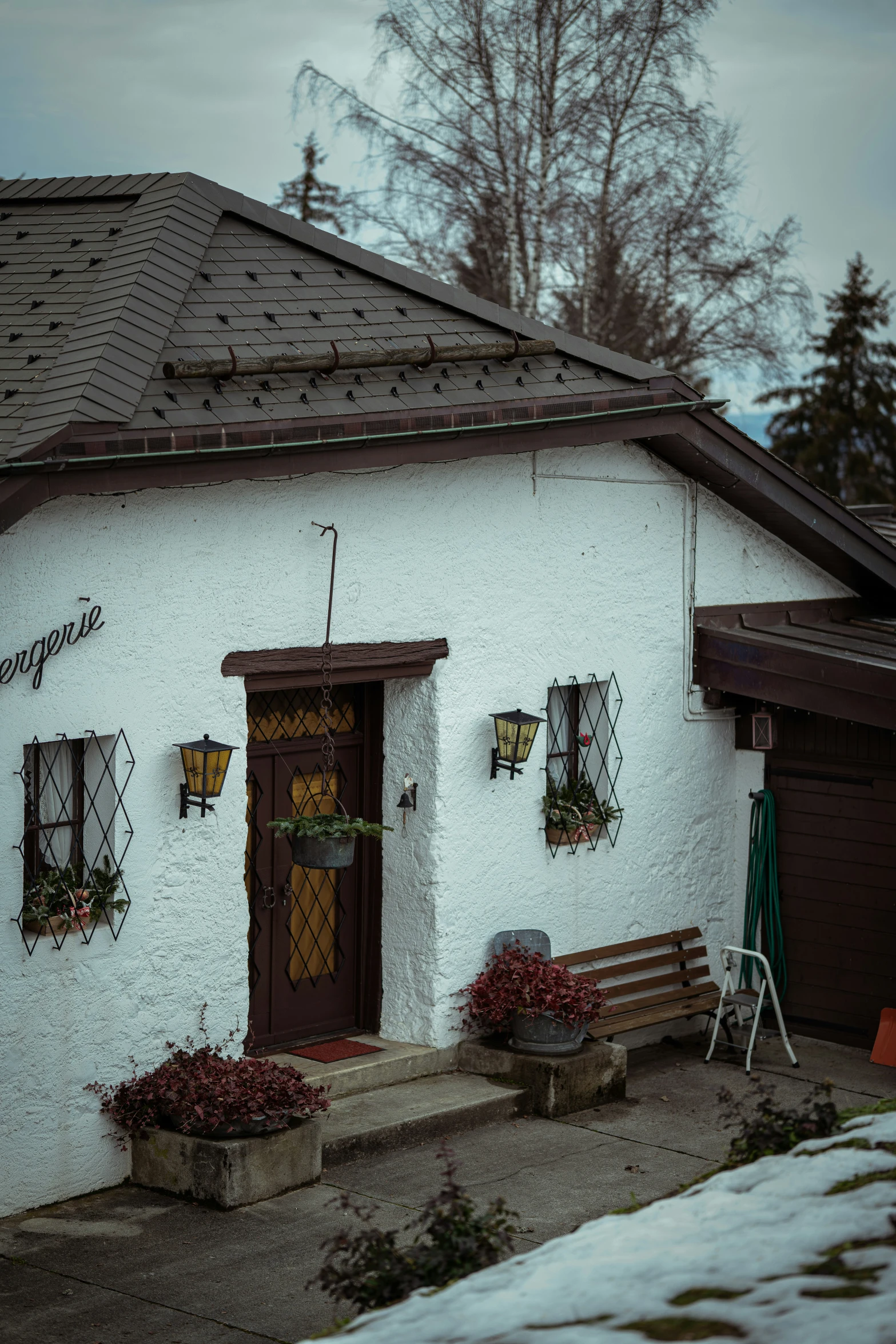 a small house sitting in the snow near a building