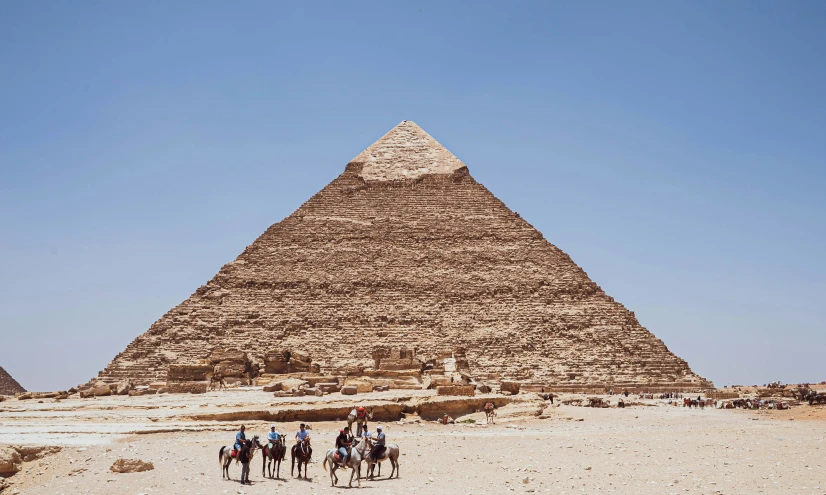 four people ride horses in front of the pyramids of giza