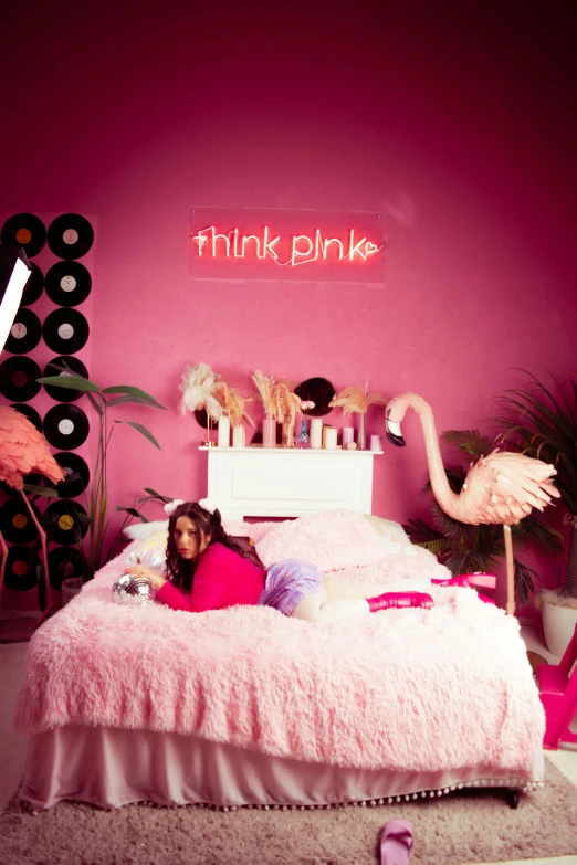 a child laying on her bed in the bedroom with pink walls and decorations