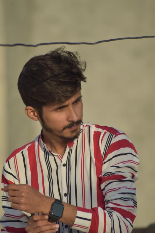 an indian man wearing a watch standing behind a fence