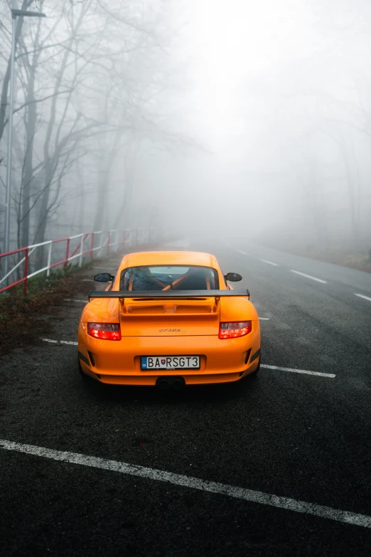 a yellow car parked on the side of a road near a forest