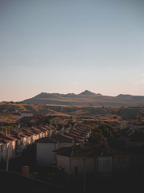 a field with houses and mountains in the background