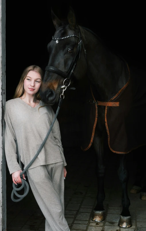 a woman standing beside a horse in an indoor stable