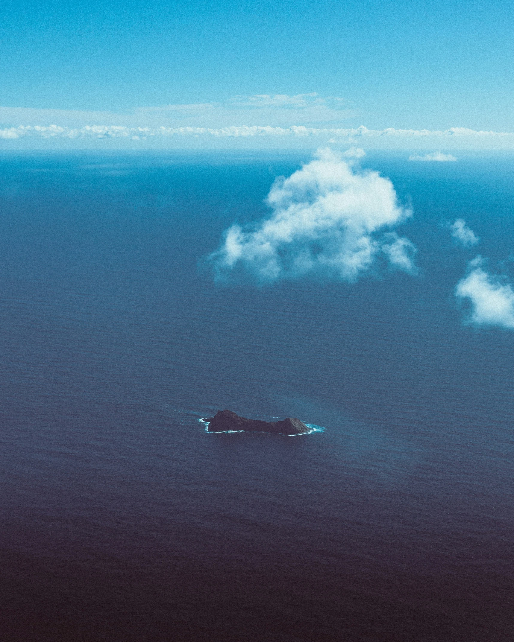 a small boat sailing in the ocean on a cloud - filled day