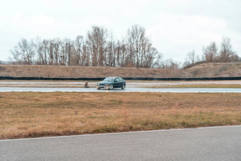 a car driving on wet road near grassy field