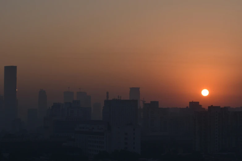 the sun rises above the skyline in the hazed sky