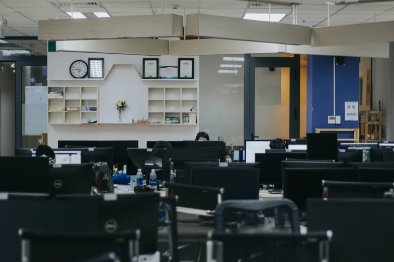 an office filled with lots of desks and black chairs