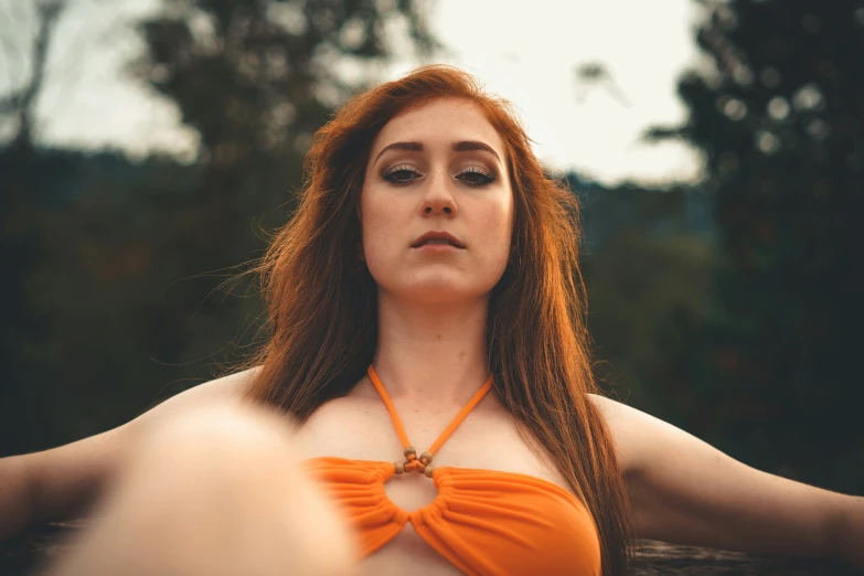 a woman with red hair wearing an orange dress is staring at another person