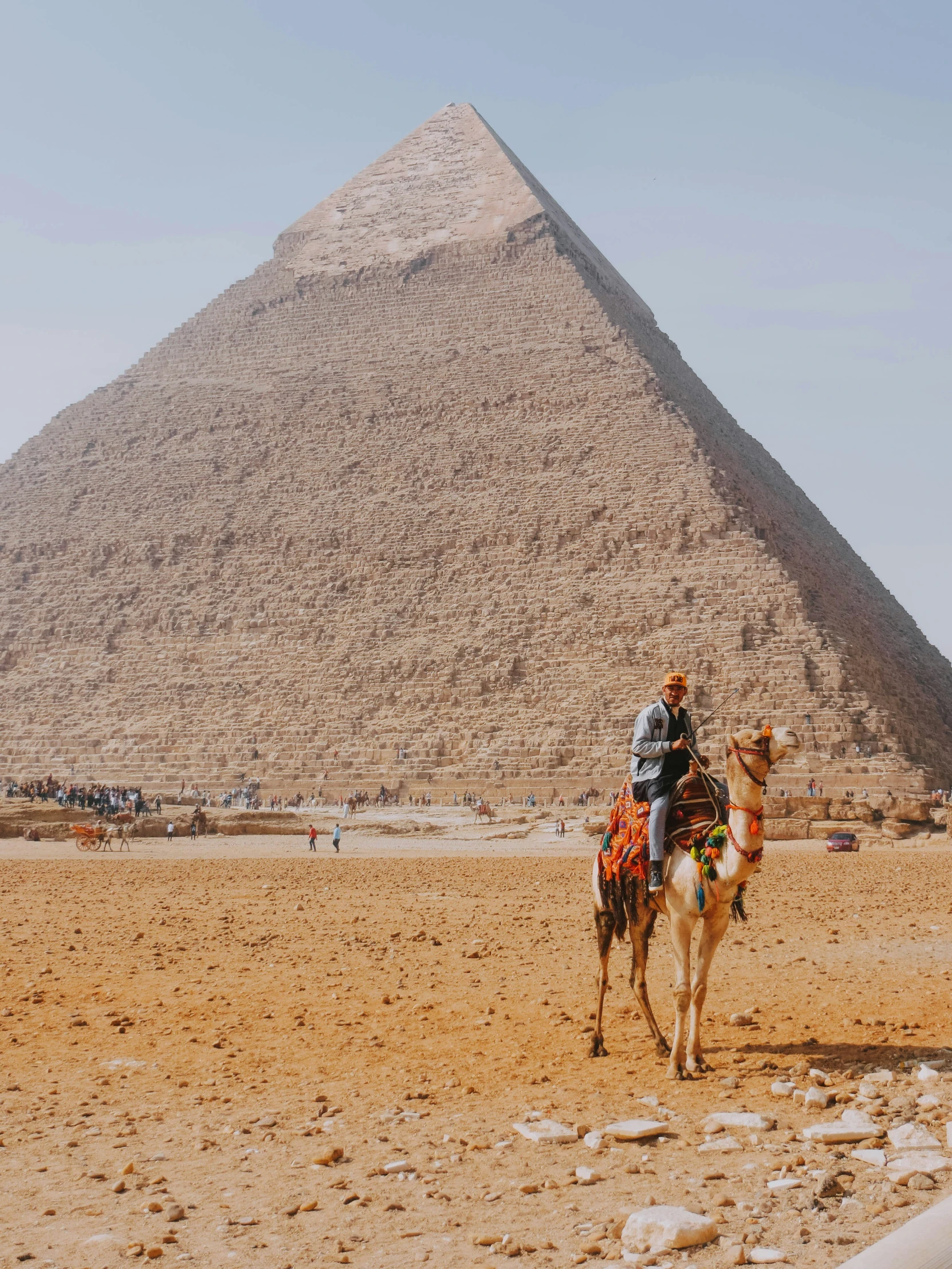 the man is riding his camel next to the huge pyramid