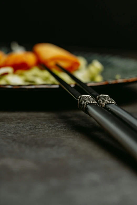 two chopsticks resting on a plate of broccoli and carrots