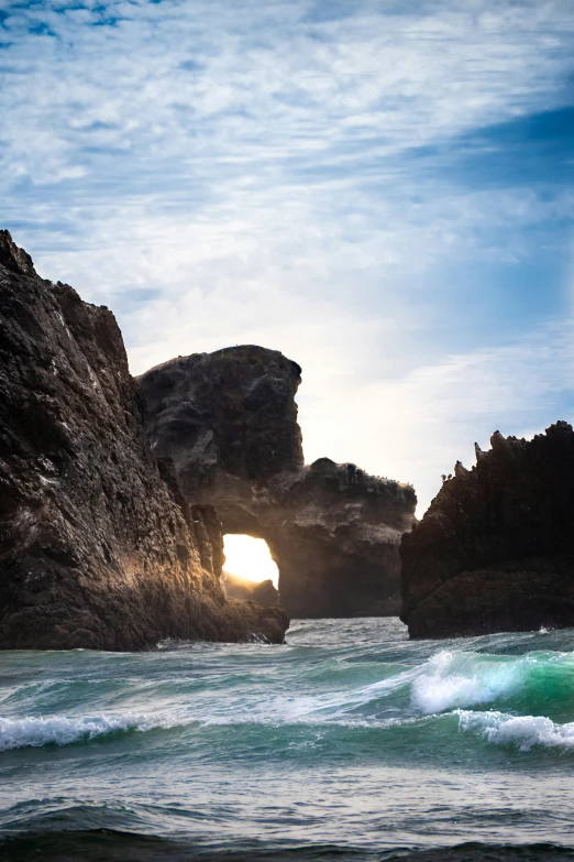 a rocky shoreline with a water cave in the background