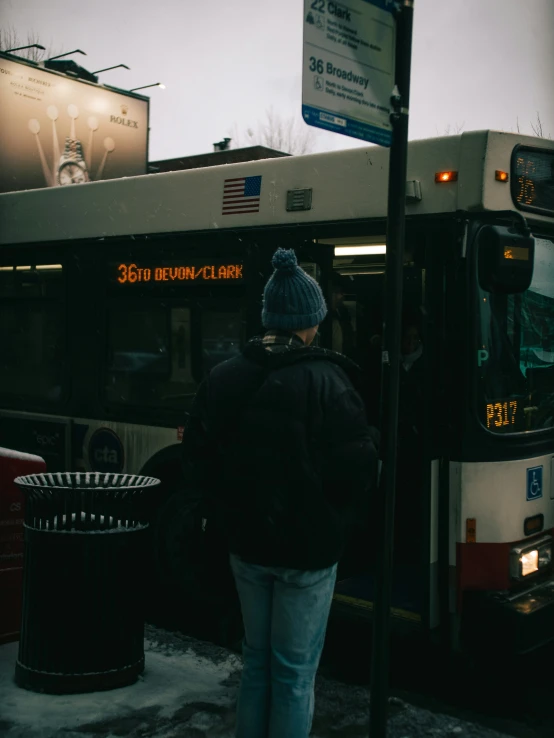 a bus at a bus stop with people entering the bus