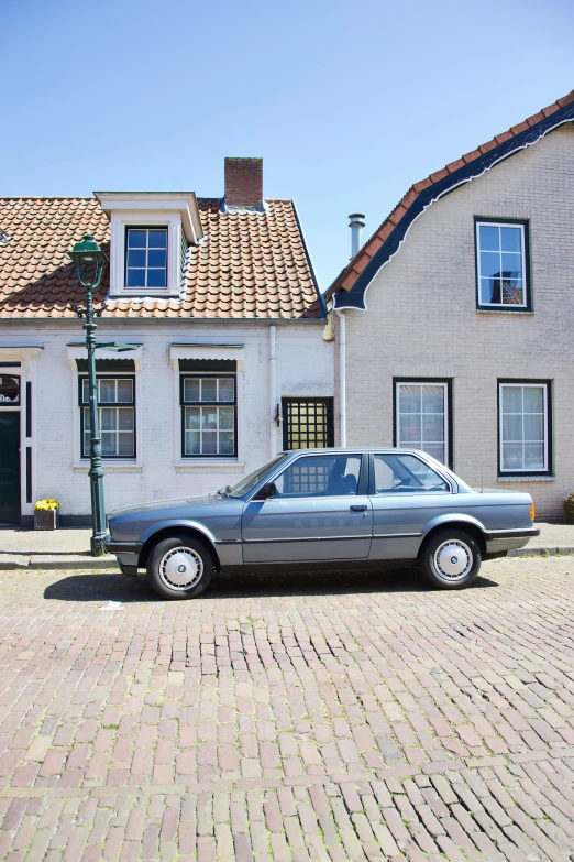 an older car sitting outside a white brick house