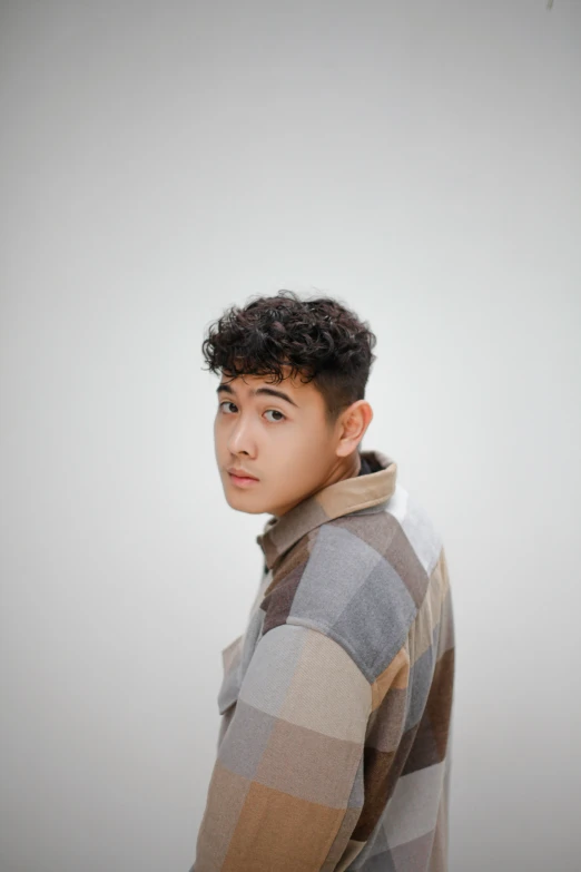 a boy with curly hair standing up in a coat