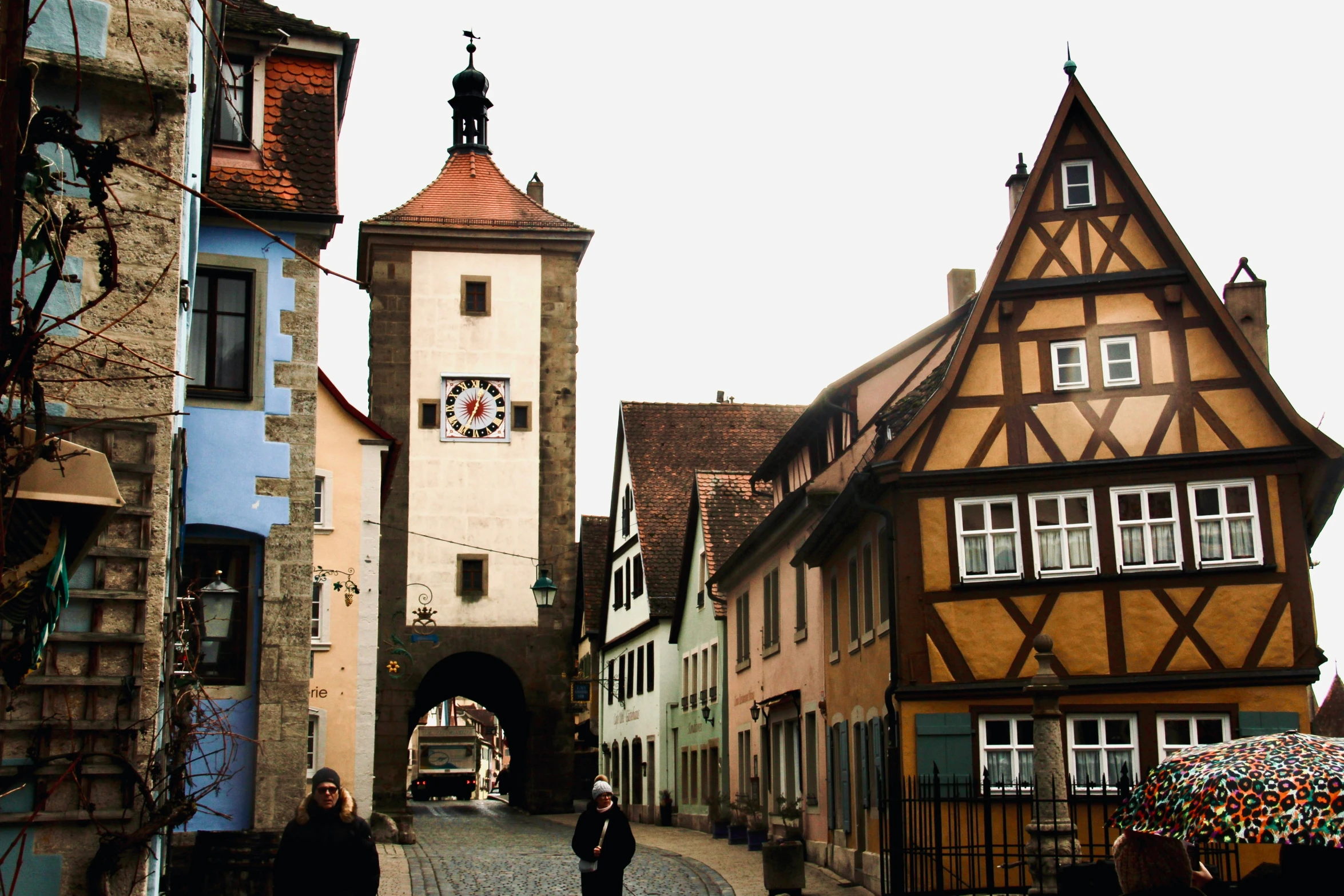 two people walking along a brick walkway between two buildings