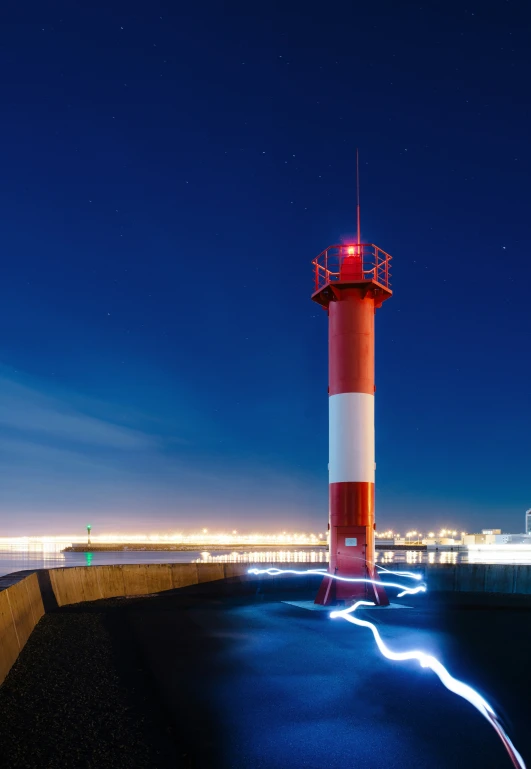 a red and white lighthouse is sitting in the middle of the night